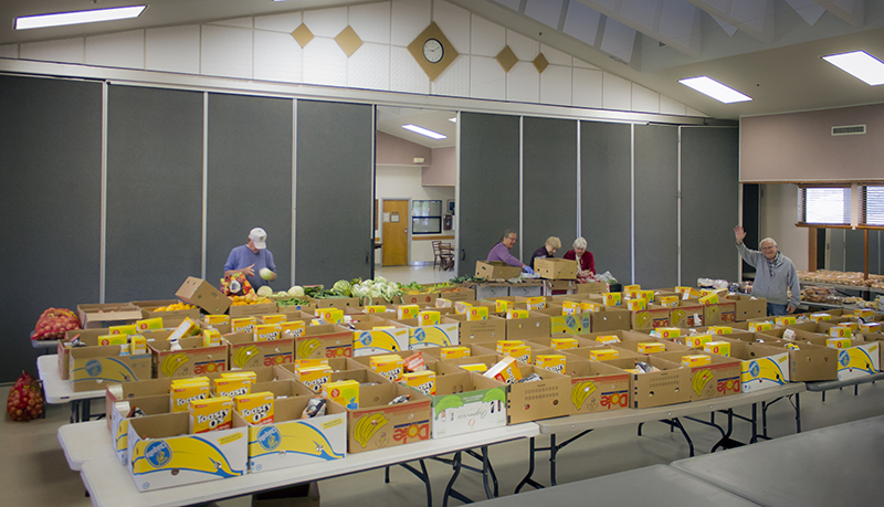 People are organizing food boxes in a community center, embodying the spirit of people helping people.
