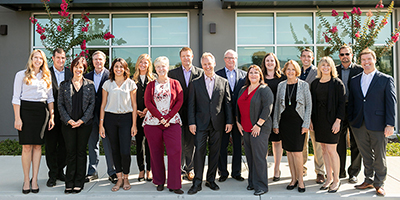 A group of people standing together outside a building, dressed in business attire.