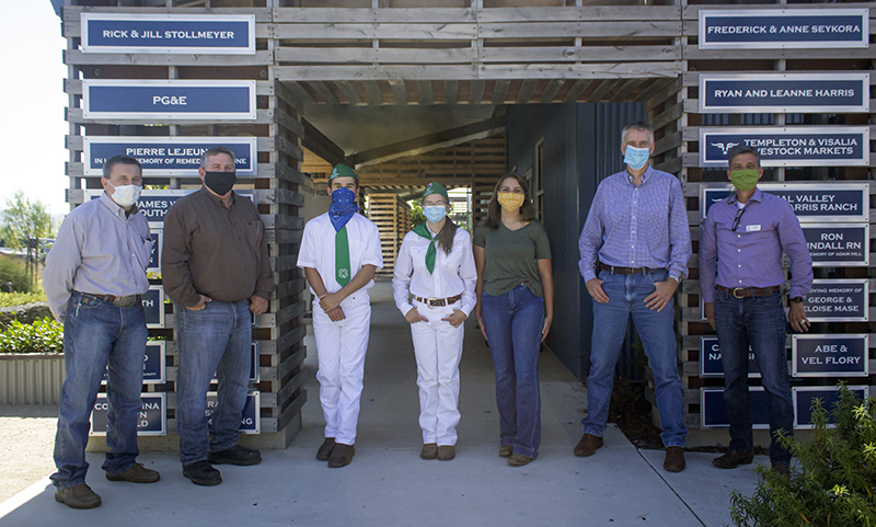 A group of people wearing masks stands in front of donor boards, possibly indicating a fundraising campaign.