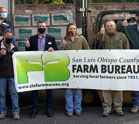 A group of people with a banner saying "San Luis Obispo County Farm Bureau," giving thumbs up.