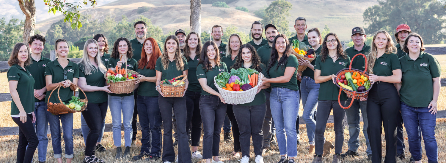 Equipo SLOFB - Sobre el equipo del Banco de Alimentos SLO El equipo del Banco de Alimentos de SLO posando al aire libre con cestas de productos frescos, destacando su compromiso en la lucha contra el hambre.