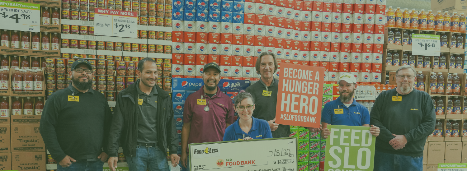A group of people in a store holding signs and a large check for the SLO Food Bank, showing corporate giving.