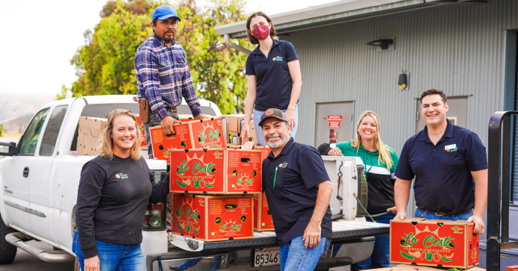 A group of people unloading boxes from a truck, likely involved in food distribution.