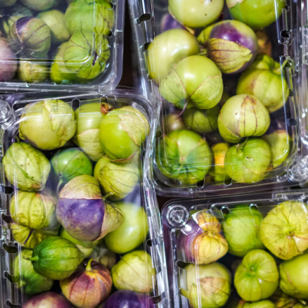 Plastic containers filled with fresh tomatillos.