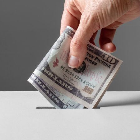 A hand is placing money into a slot, possibly related to food bank donations