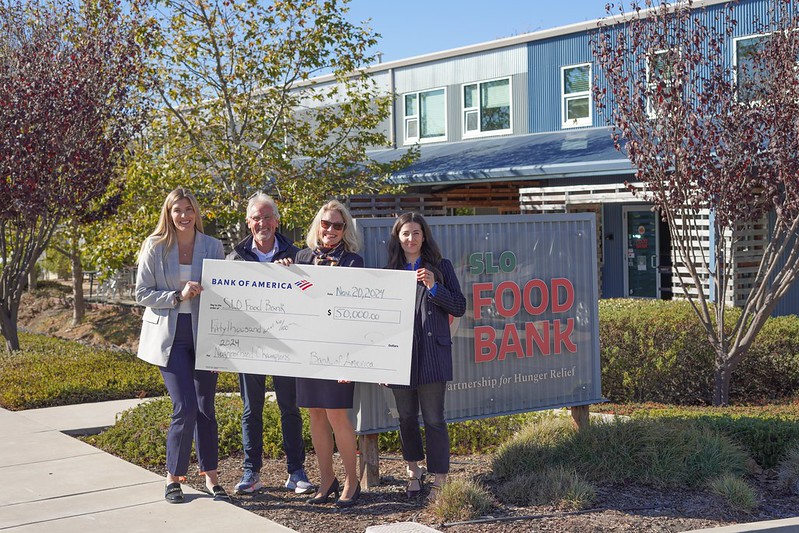 Four people hold a large check for $50,000 from Bank of America to SLO Food Bank, labeled with