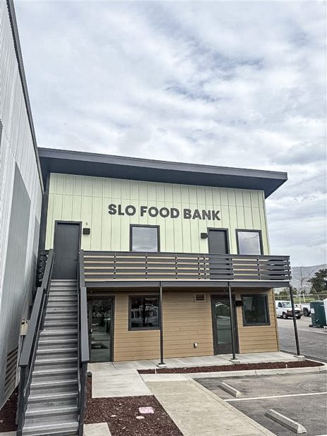 The SLO Food Bank Pantry A building labeled "SLO Food Bank," featuring two stories with stairs leading to the upper level.