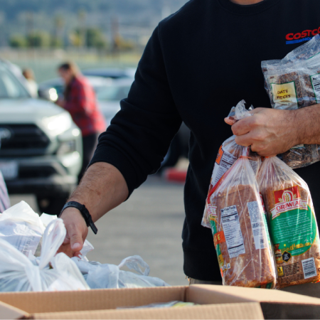 People distributing groceries outdoors, possibly participating in a California food assistance program.