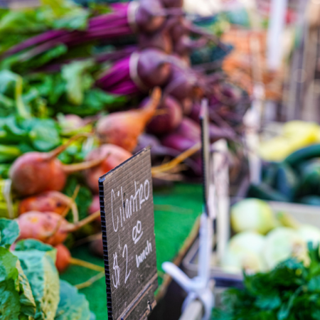 Fresh produce at a farmers market, including leafy greens and root vegetables. Market Match CalFresh applies.